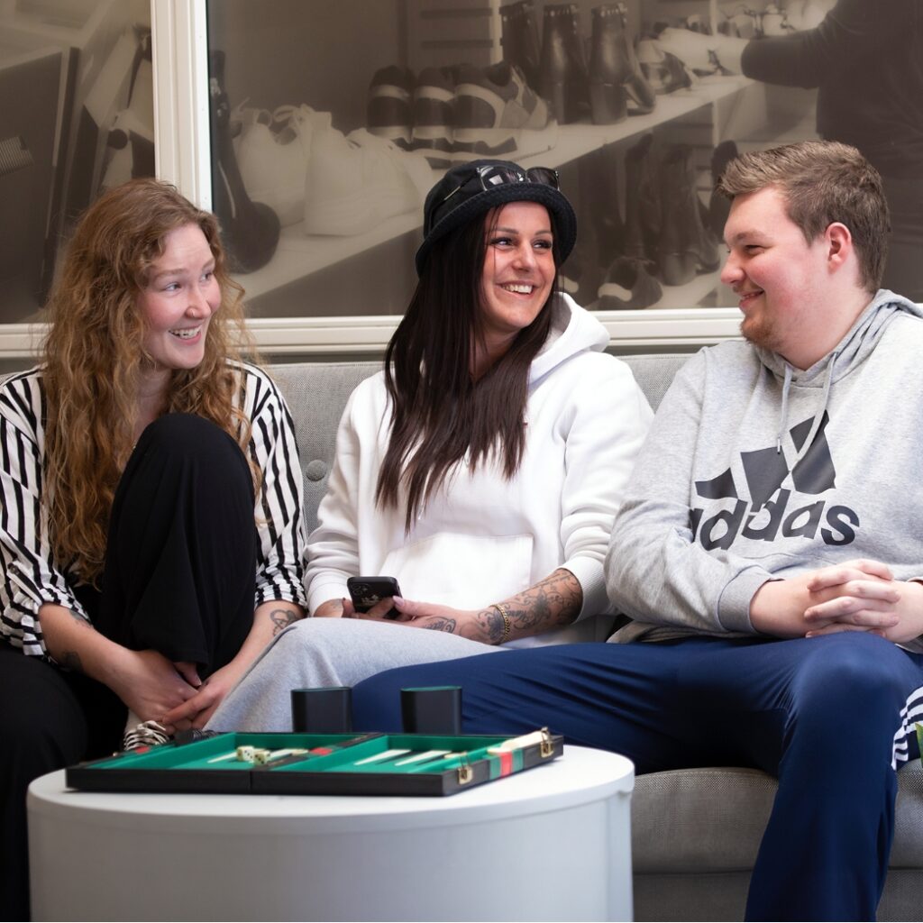 Tre elever fra NEG sidder i en sofa med et spil backgammon foran dem. Eleverne ser glade ud.
