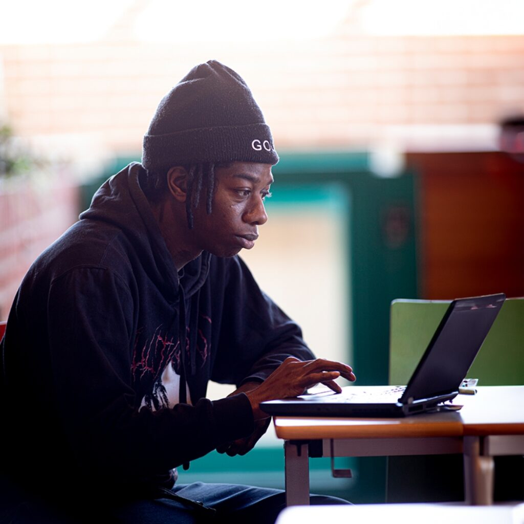 En ung mand sidder og kigger på sin laptop.
